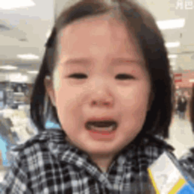 a little girl is crying in a store while holding a box of milk .