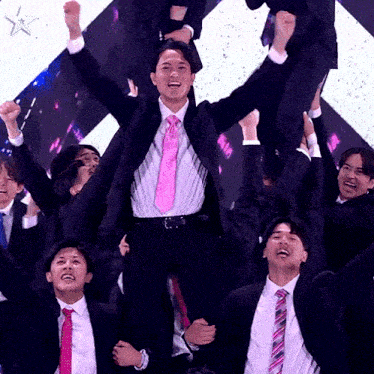 a man in a suit and pink tie is being lifted in the air