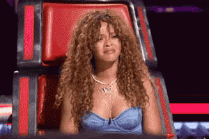 a woman with curly hair is sitting in a red chair with her eyes closed .