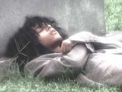 a man in a suit is laying in the grass with his eyes closed