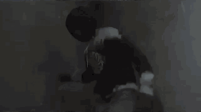 a person is standing in a dark room with a shadow of a person behind them .