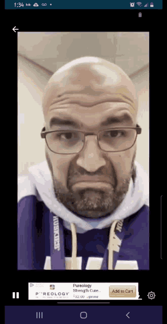 a man wearing glasses and a purple minnesota vikings hoodie