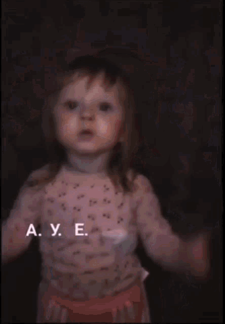 a little girl wearing a white polka dot shirt is making a middle finger sign