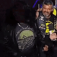 two men are standing next to each other in a dark room . one of the men is wearing a skull shirt .