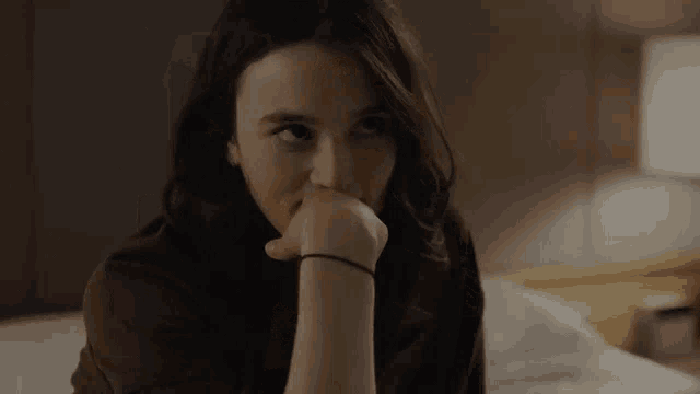 a woman is laying on a bed with her hand on her face and looking at the camera .