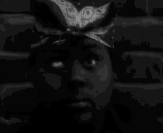 a black and white photo of a woman wearing a bandana and a hat .