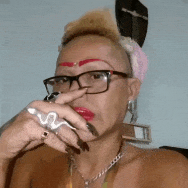 a woman wearing glasses and a snake ring is smoking a cigarette .