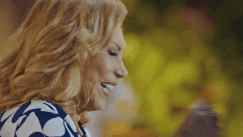 a woman in a blue and white polka dot dress is making a funny face with her hair blowing in the wind .
