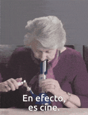 an elderly woman is smoking a bong with the words en efecto es cine behind her