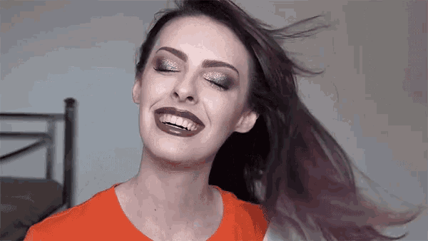 a woman with purple hair is smiling with her mouth open
