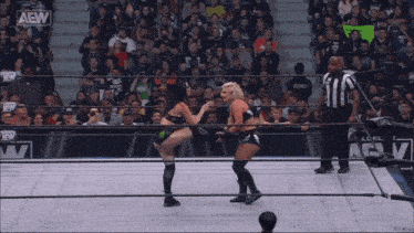 two women are wrestling in a ring with a crowd watching and a sign that says aew on it