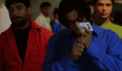 a man in a blue shirt is holding a cell phone in his right hand