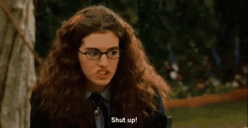 a woman with curly hair and glasses is making a funny face and says `` shut up '' .