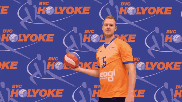 a man throws a ball in front of a blue background that says bvc holyoke