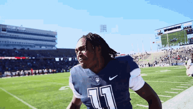 a football player wearing a number 11 jersey stands on the field