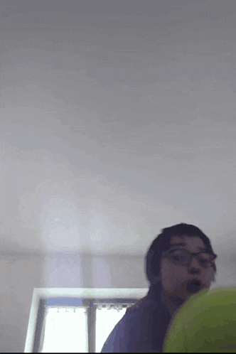 a person wearing glasses is standing in a room with a window