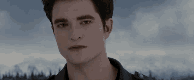 a close up of a young man 's face with a cloudy sky in the background