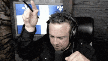 a man wearing headphones and a microphone holds up his finger
