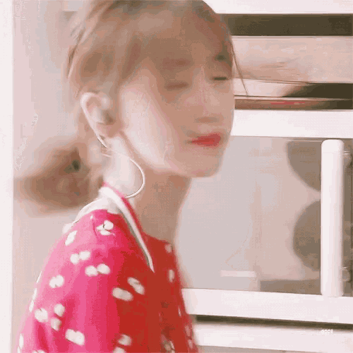 a woman in a red dress is standing in front of a microwave oven .
