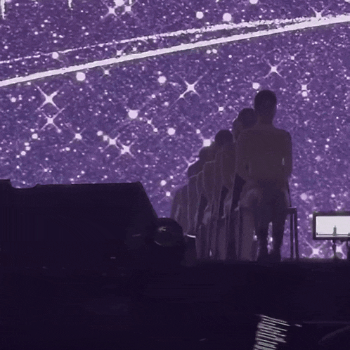 a group of people are standing on a stage in front of a purple background