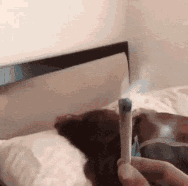 a person is smoking a cigarette on a bed