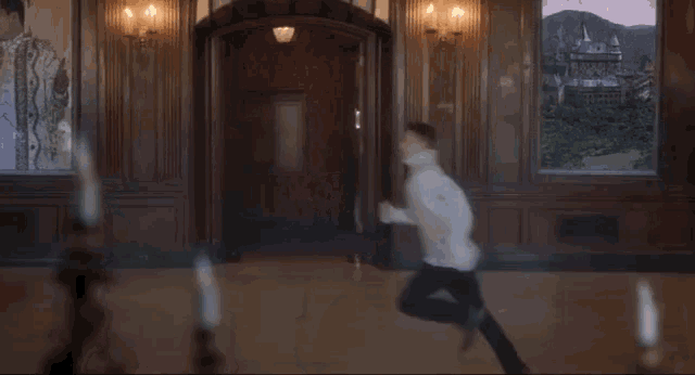 a man in a white shirt is running through a room