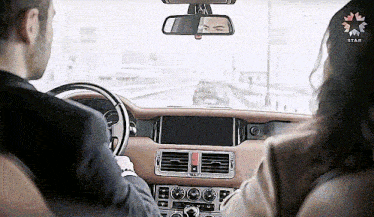 a man is driving a car with a woman sitting in the back seat .