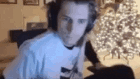 a man is wearing headphones while sitting in front of a christmas tree .