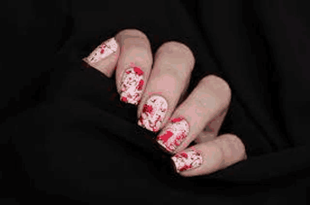 a close up of a woman 's nails with blood splatters on them .