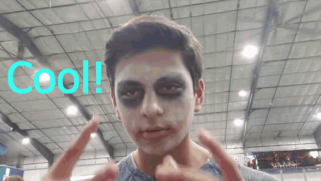 a man with a joker makeup on his face and the word cool in blue behind him