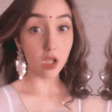 a close up of a woman making a funny face while wearing earrings .