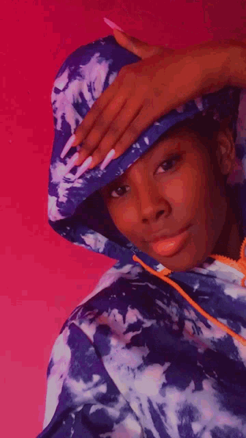 a woman wearing a tie dye hoodie covering her face