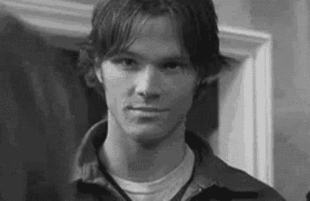 a black and white photo of a man wearing a jacket and a white shirt .