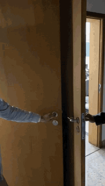 a person opens a door with their hand and another person opens the door with their hand