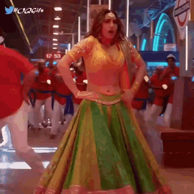a woman in a yellow top and green skirt is dancing in a room .