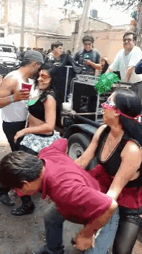 a group of people are dancing on the street and one of them is wearing a mask and sunglasses
