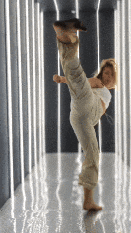 a woman is kicking her leg in the air in a hallway