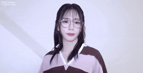a young woman wearing glasses and a pink sweater is giving the middle finger .