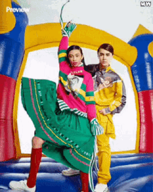 a woman in a green skirt is standing next to a man in a yellow jacket