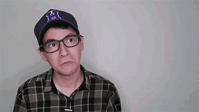 a man wearing glasses and a baseball cap with the letter h on it