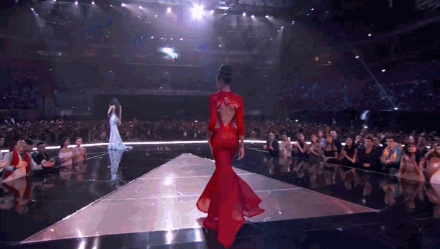 a woman in a red dress is walking down the runway