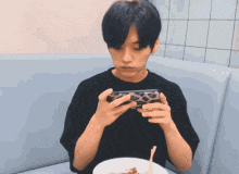 a young man is sitting on a couch playing a game on his phone