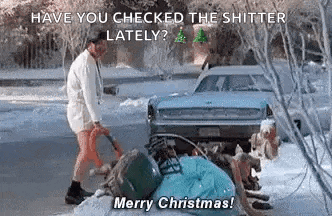 a man in a bathrobe is standing in the snow next to a car and a pile of trash .