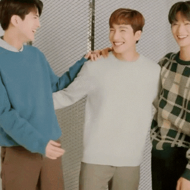a man in a blue sweater is standing next to two other men in plaid sweaters