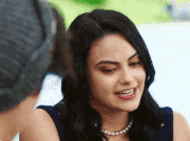 a close up of a woman wearing a pearl necklace and smiling