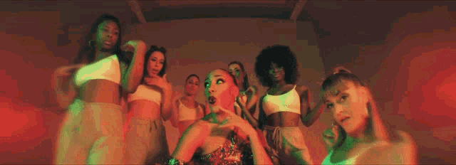 a group of women are dancing in a room with green lights behind them