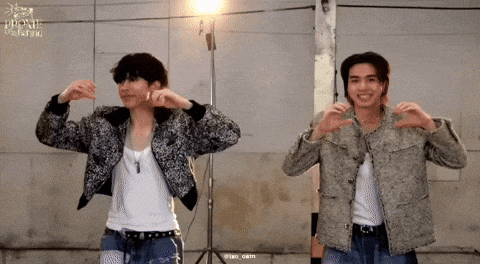 two men are standing next to each other making a heart shape with their hands