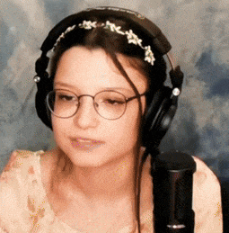 a woman wearing headphones and glasses is looking at the camera .
