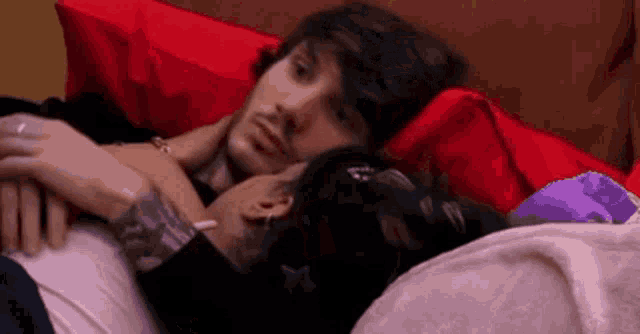 two men are laying in bed hugging each other .