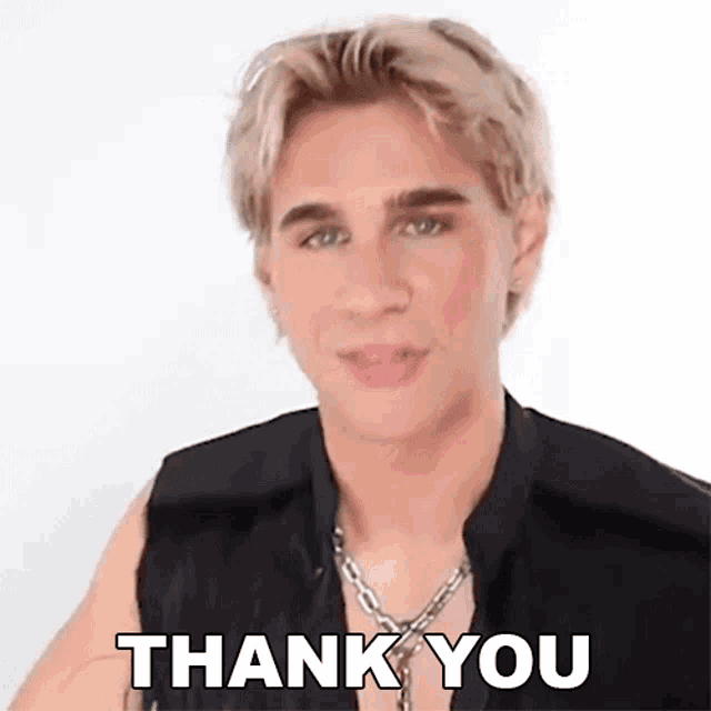 a young man is wearing a black vest and a necklace and is saying thank you .